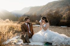 a bride and groom sitting on a blanket in the desert