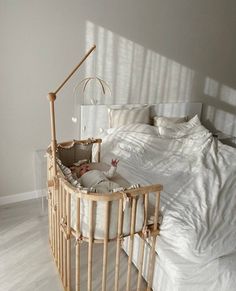 a baby in a crib next to a bed with white sheets and pillows on it