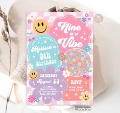 a pink and blue birthday card with smiley faces on it, next to some flowers