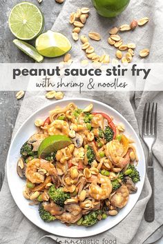 a white plate topped with shrimp, broccoli and cashews next to a lime