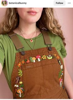 a woman with long hair wearing overalls and a green t - shirt is posing for the camera