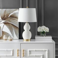 a white lamp sitting on top of a dresser