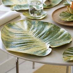 a table topped with plates covered in leafy green and yellow dishes next to a vase filled with flowers