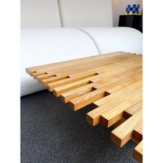 a wooden table sitting on top of a carpeted floor next to a white couch