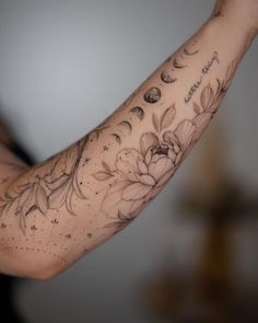 a woman's arm with flowers and moon tattoos on her left arm is shown