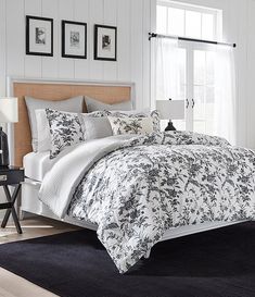 a bed with white and black comforters in a bedroom next to a window,