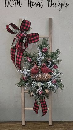 Wood ladder decorated with winter greens, berries, iced branches and cardinals on a pine cone. Finished with a buffalo check bow. #dcmfloraldesigns Christmas Ladder Decor, Ladder Christmas Decor, Christmas Ladders Ideas, Old Ladder Decor, Picture Frame Wreaths, Iced Branches, Frame Wreaths, Christmas Ladder, Cemetery Ideas