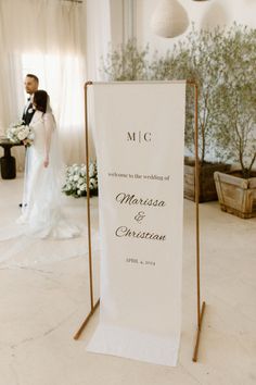 a couple standing next to each other in front of a white sign with the words mr and mrs on it