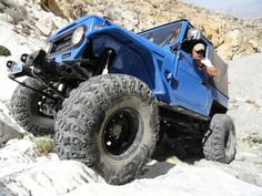 a man driving a blue four - wheeler on top of a rocky hill in the desert