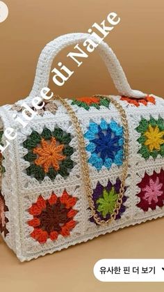 a white crocheted bag with multicolored flowers on the front and sides