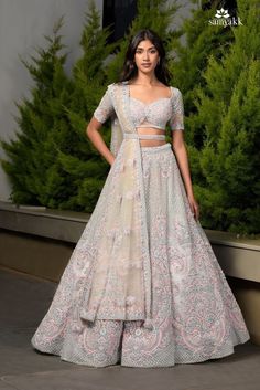 a woman in a white and pink lehenga with matching crop top, skirt and blouse