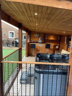 an outdoor kitchen and living room area with wood paneling, metal railings and black appliances