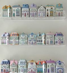 two shelves filled with miniature houses on top of each other in front of a white wall