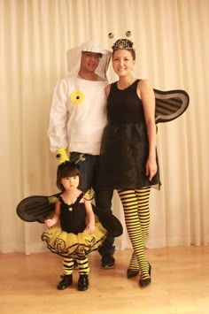 two adults and a child dressed up as bee costumes, standing in front of a curtain