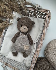 a brown teddy bear sitting on top of a white blanket next to some balls of yarn