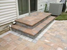 a brick patio with steps leading up to an air conditioner