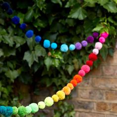 colorful pom - poms are hanging from a tree