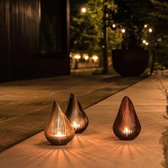 three wooden vases sitting on top of a cement floor next to plants and lights