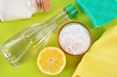 a green table topped with lots of different types of cleaning supplies next to lemon slices