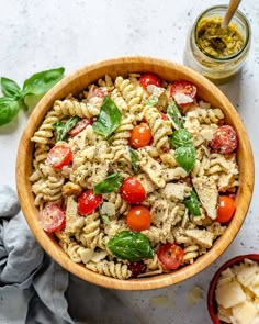 a wooden bowl filled with pasta salad next to two small bowls