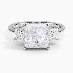 a princess cut diamond ring with three side stones on the band and shoulders, in white gold