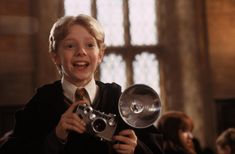 a young boy holding a camera in front of his face while wearing a harry potter costume