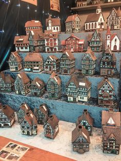 a display case filled with lots of small houses on top of a wooden table covered in snow