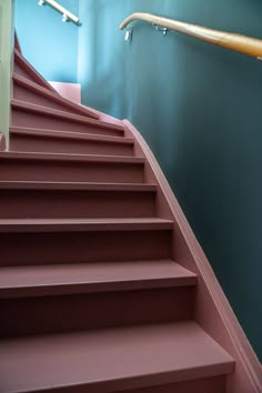 a set of pink stairs leading up to a blue wall with white railing and handrails