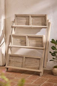 three wooden shelves sitting next to each other on a tile floor near a potted plant