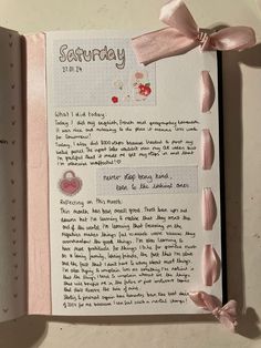 an open book with pink ribbon and writing on it