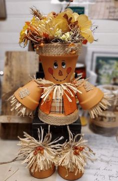 a scarecrow made out of pumpkins and corn stalks with flowers in it's head