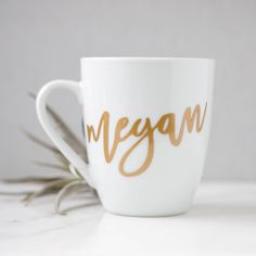 a white coffee cup with the word vegan written on it and an air plant