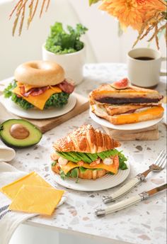 two sandwiches on plates with cheese, lettuce and other foods in the background