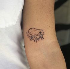 a small frog tattoo on the arm