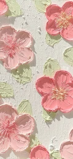 some pink flowers and green leaves on a white surface