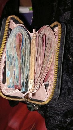 an open purse filled with lots of different colored thread and zippers on the inside