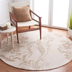 a living room with a chair, table and rug on the wooden floor next to a window