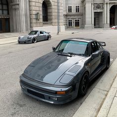 two cars are parked on the side of the road in front of an old building