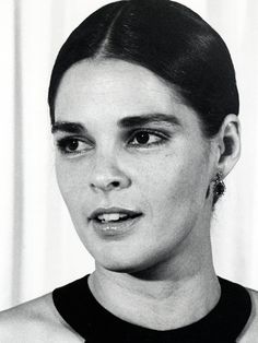 a black and white photo of a woman with earrings on her head, looking at the camera