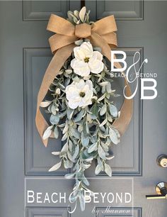 the front door is decorated with white flowers and greenery as well as a brown bow