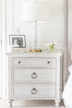 a white dresser with two drawers and a lamp