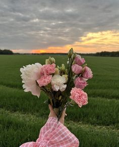 a person holding flowers in front of a field