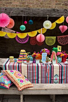 an outdoor table with colorful decorations and paper fans