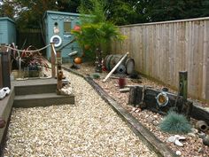 an outdoor area with gravel, rocks and wooden fenced in areas that have various items on them