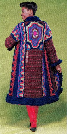 a woman in a crocheted coat and red pants