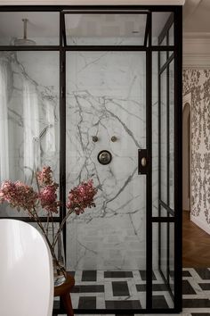 a bathroom with marble walls and flooring next to a bathtub filled with flowers