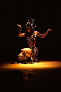 a woman dressed in costume kneeling on the ground with her arms out and legs crossed