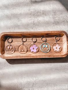 six wooden keychains with different designs on them in a wood holder against a concrete wall