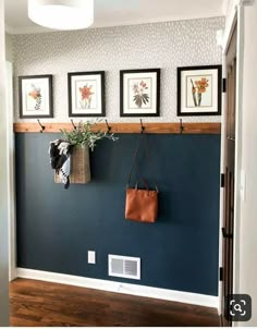 a blue wall with pictures on it and a brown bag hanging from the hooks in front