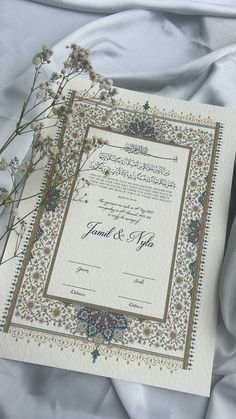 an ornate wedding card with flowers on the front and back, sitting on a white sheet